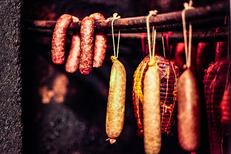 házi készítésű füstölőben lógó kolbász és sonka